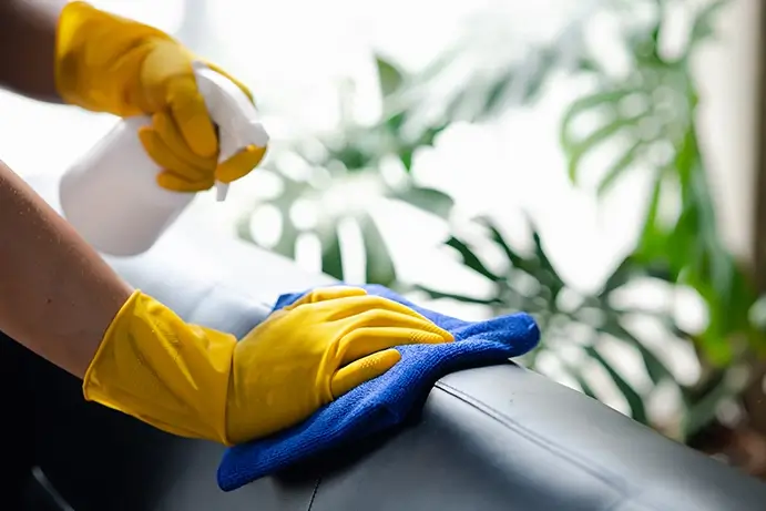 Une personne nettoie une surface avec des gants jaunes.