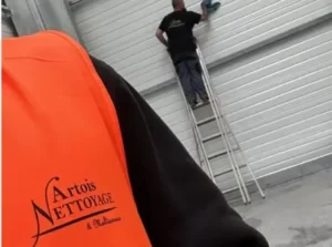 Un homme se tient sur une échelle à côté d'une porte de garage.