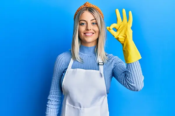 Une femme avec un tablier et des gants en caoutchouc