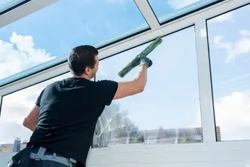 Nettoyage d'une vitre par un homme.